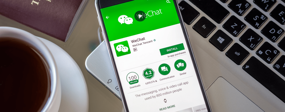 A phone with WeChat displayed on the screen, resting on a laptop keyboard.