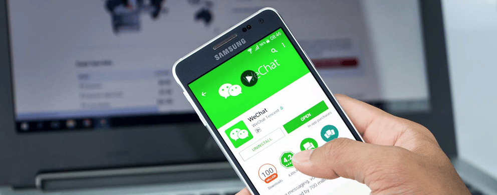 A person holding a phone with WeChat displayed on the screen.
